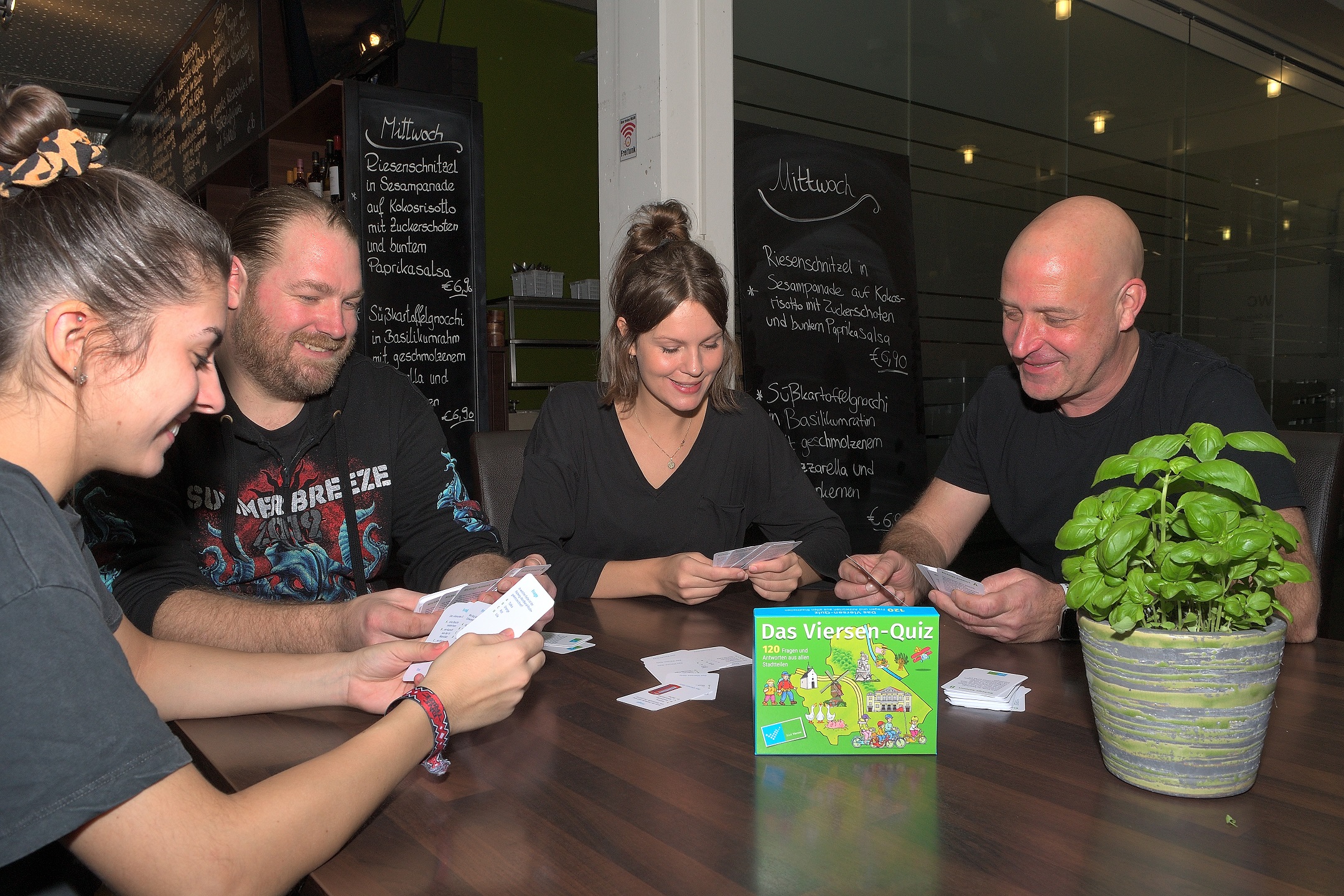 Vier Menschen sitzen fröhlich an einem Tisch und spielen das Viersen-Quiz (Foto: Stadt Viersen)