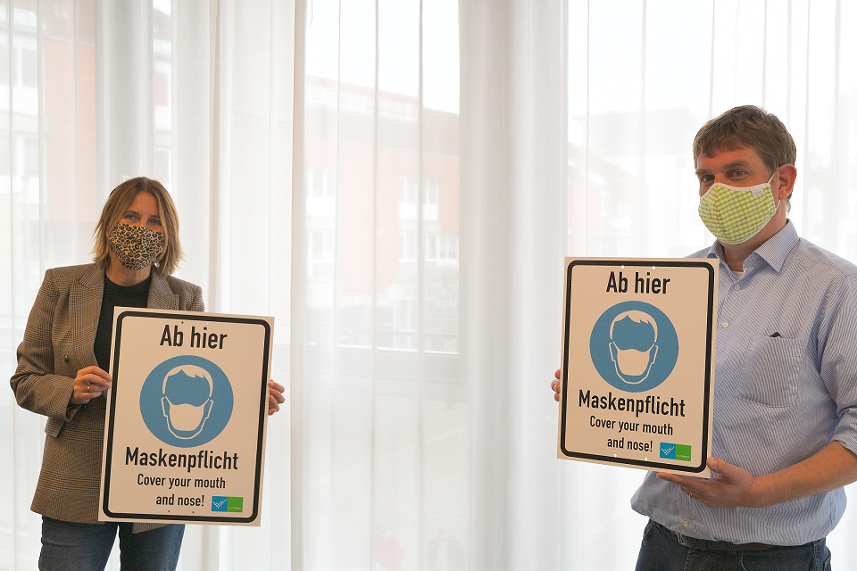 Bürgermeisterin Sabine Anemüller und Markus Kampe, Fachbereichsleiter Städtische Betriebe, zeigen Muster der Schilder, mit denen auf die Maskenpflicht hingewiesen wird (Foto: Stadt Viersen)