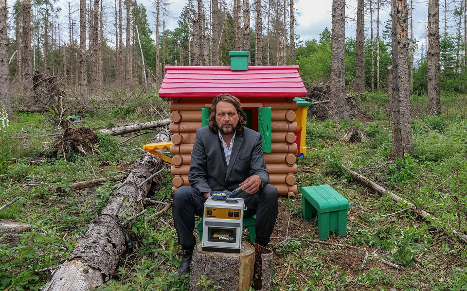 Jan Philip Scheibe mit einer Kinderspielhütte und einem Miniatur-Ofen im Wald (Foto: VG Bild)