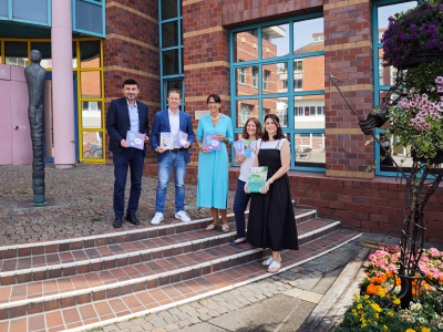 Menschen präsentieren Bücher und Prospekte vor Bibliothek