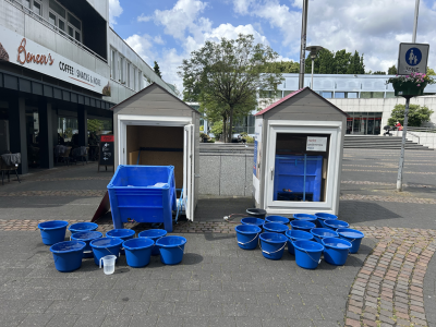Das Bild zeigt eines der Modellhäuser mit den Resten des Eisblocks in einer Wanne und zahlreichen Wassereimern (Foto: Stadt Viersen) 