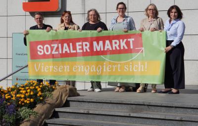 Beteiligte präsentieren Banner zum Sozialen Markt
