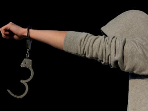 Mensch mit Kapuzenpulli und geöffneter Handschelle